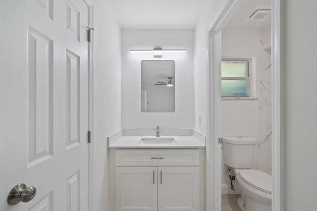 a bathroom with a toilet a sink a vanity and mirror