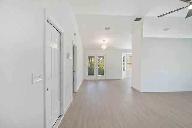 a view of a hallway with wooden floor and a bathroom