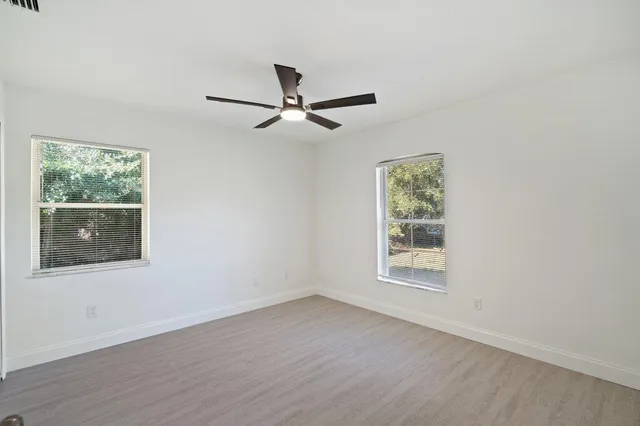 a view of an empty room with a window and wooden floor