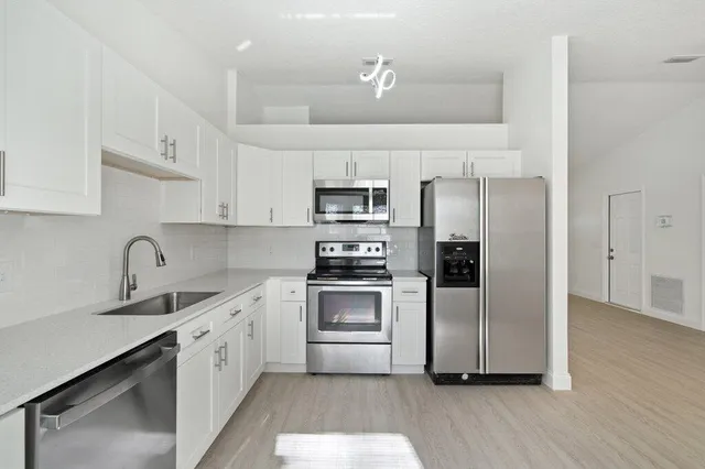 a kitchen with stainless steel appliances granite countertop a sink a stove a refrigerator and cabinets