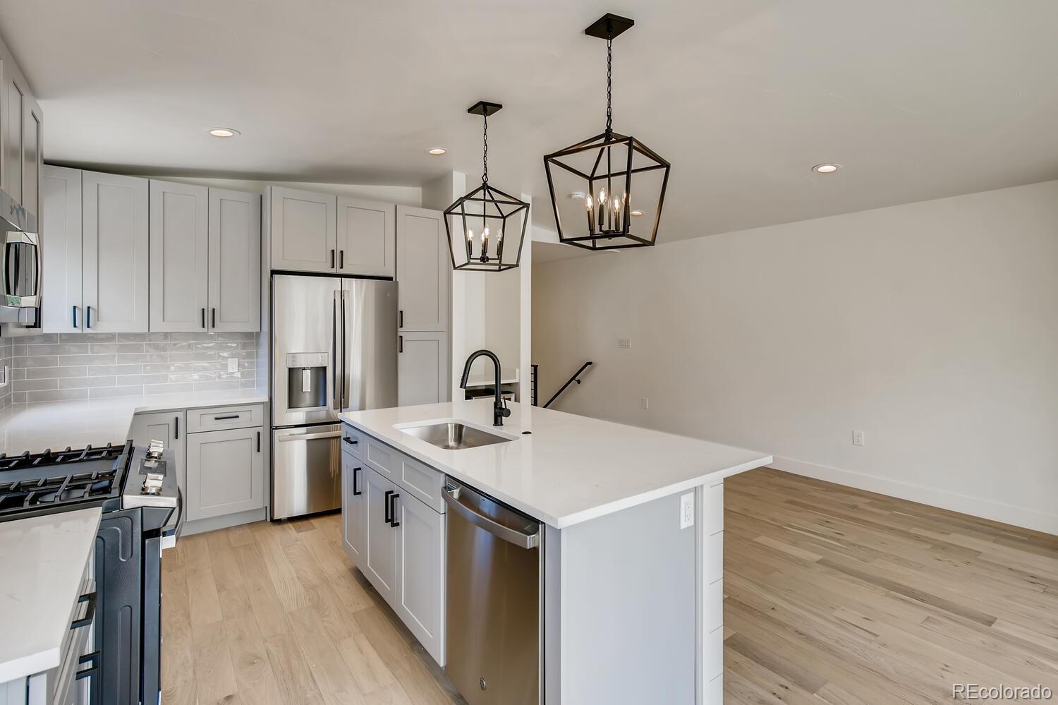 949 Raleigh Street, Unit 2 Denver, CO 80204 - Photo 14 of 26 a kitchen with stainless steel appliances a sink a refrigerator a stove a microwave and white cabinets