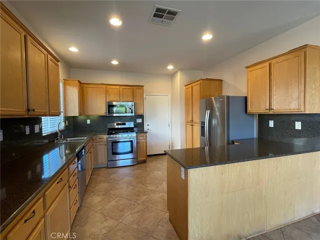 a large kitchen with stainless steel appliances kitchen island granite countertop a refrigerator a stove top oven a sink and dishwasher