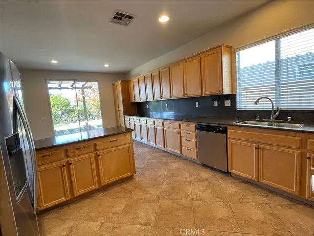 a kitchen with stainless steel appliances granite countertop a sink a stove a refrigerator cabinets and a window