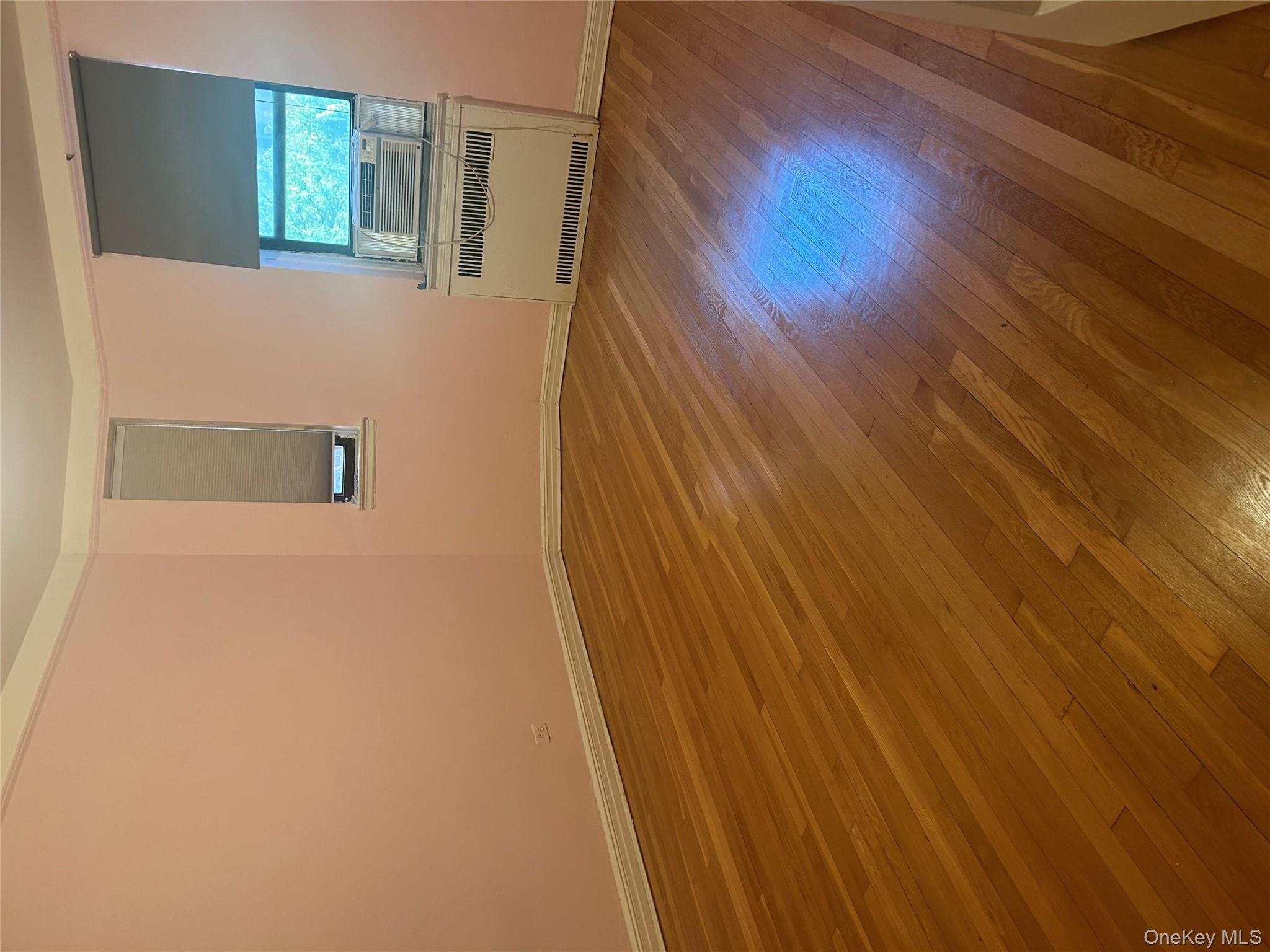 15501 90th Avenue, Unit 3M Queens, NY 11432 - Photo 6 of 6 an empty room with wooden floor and windows