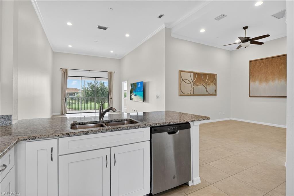9386 Pocida Court, Unit 202 Naples, FL 34119 - Photo 11 of 38 Kitchen with stainless steel dishwasher, dark stone countertops, white cabinetry, ornamental molding, and a ceiling fan
