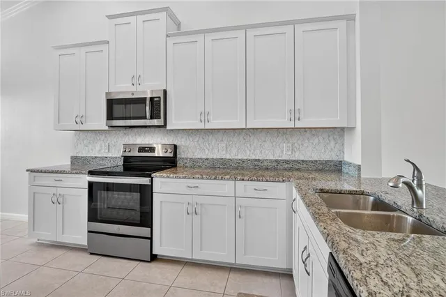 a kitchen with stainless steel appliances granite countertop a sink a stove and a refrigerator