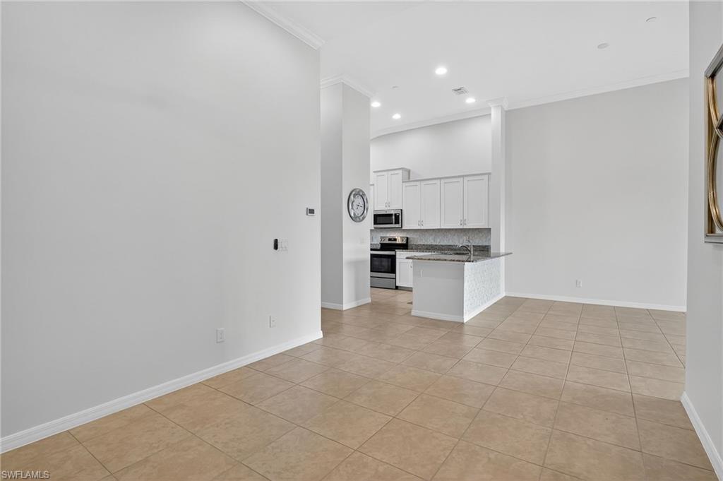 9386 Pocida Court, Unit 202 Naples, FL 34119 - Photo 16 of 38 Unfurnished living room featuring ornamental molding, light tile patterned floors, recessed lighting, and a high ceiling