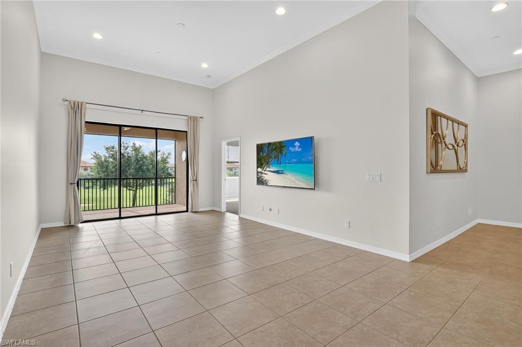 9386 Pocida Court, Unit 202 Naples, FL 34119 - Photo 18 of 38 Unfurnished living room with light tile patterned flooring, crown molding, recessed lighting, and a high ceiling