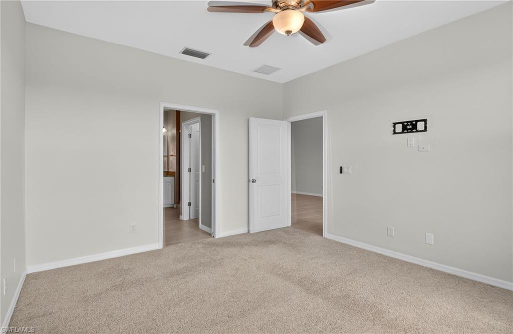 9386 Pocida Court, Unit 202 Naples, FL 34119 - Photo 28 of 38 Unfurnished bedroom featuring light carpet, ensuite bathroom, and ceiling fan