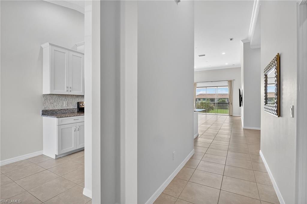 9386 Pocida Court, Unit 202 Naples, FL 34119 - Photo 4 of 38 Corridor featuring light tile patterned flooring and ornamental molding