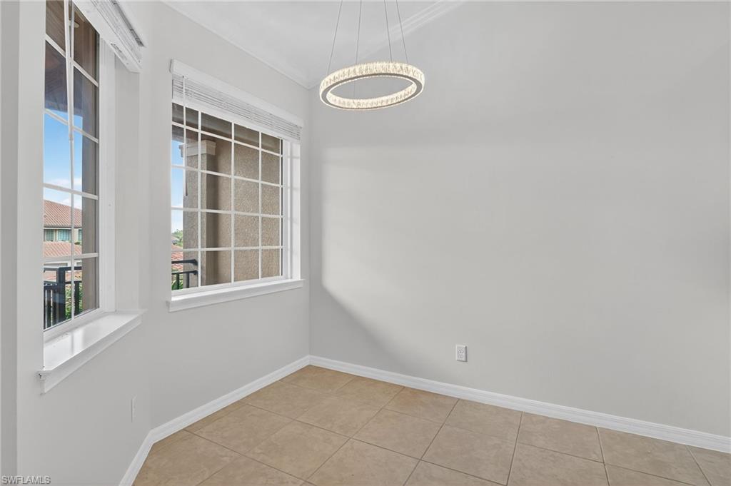 9386 Pocida Court, Unit 202 Naples, FL 34119 - Photo 6 of 38 Tiled empty room featuring a chandelier and ornamental molding