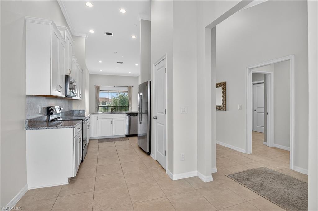 9386 Pocida Court, Unit 202 Naples, FL 34119 - Photo 8 of 38 Kitchen featuring appliances with stainless steel finishes, light tile patterned floors, dark stone countertops, white cabinets, and recessed lighting