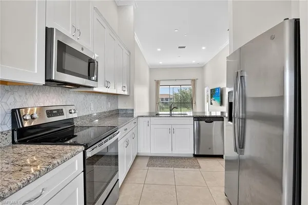 a kitchen with granite countertop a sink and white cabinets