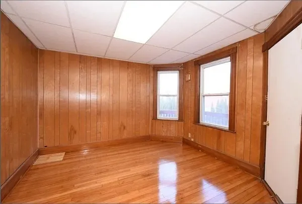 a view of an empty room with a window and wooden floor
