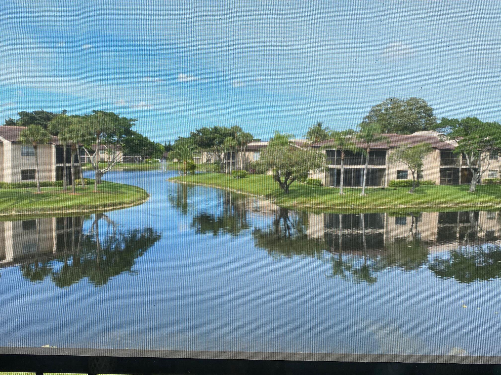 9285 Vista Del Lago, Unit 36F Boca Raton, FL 33428 - Photo 19 of 24 a view of a lake with a big yard and large trees
