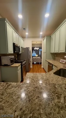 a large kitchen with kitchen island granite countertop a stove top oven a sink a counter space and cabinets