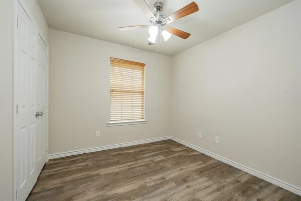 an empty room with a window and a fan
