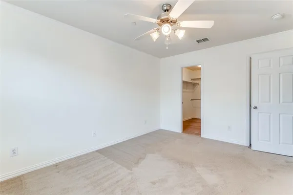 an empty room with an entryway and chandelier fan