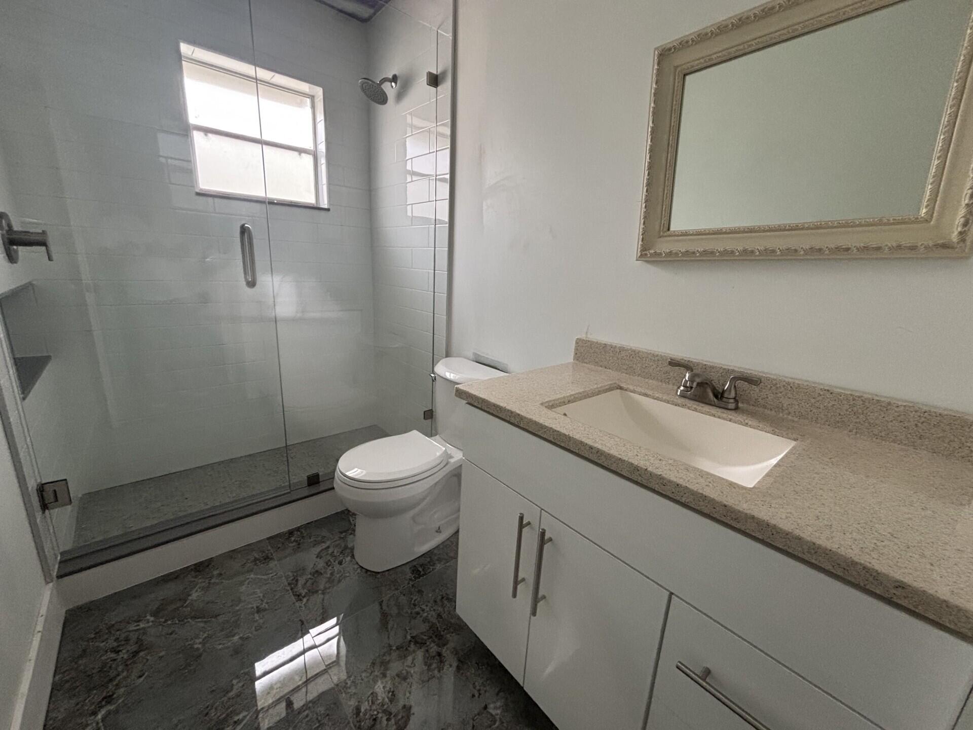 1160 East 12th Street Stuart, FL 34996 - Photo 14 of 25 a bathroom with a granite countertop sink mirror vanity and toilet