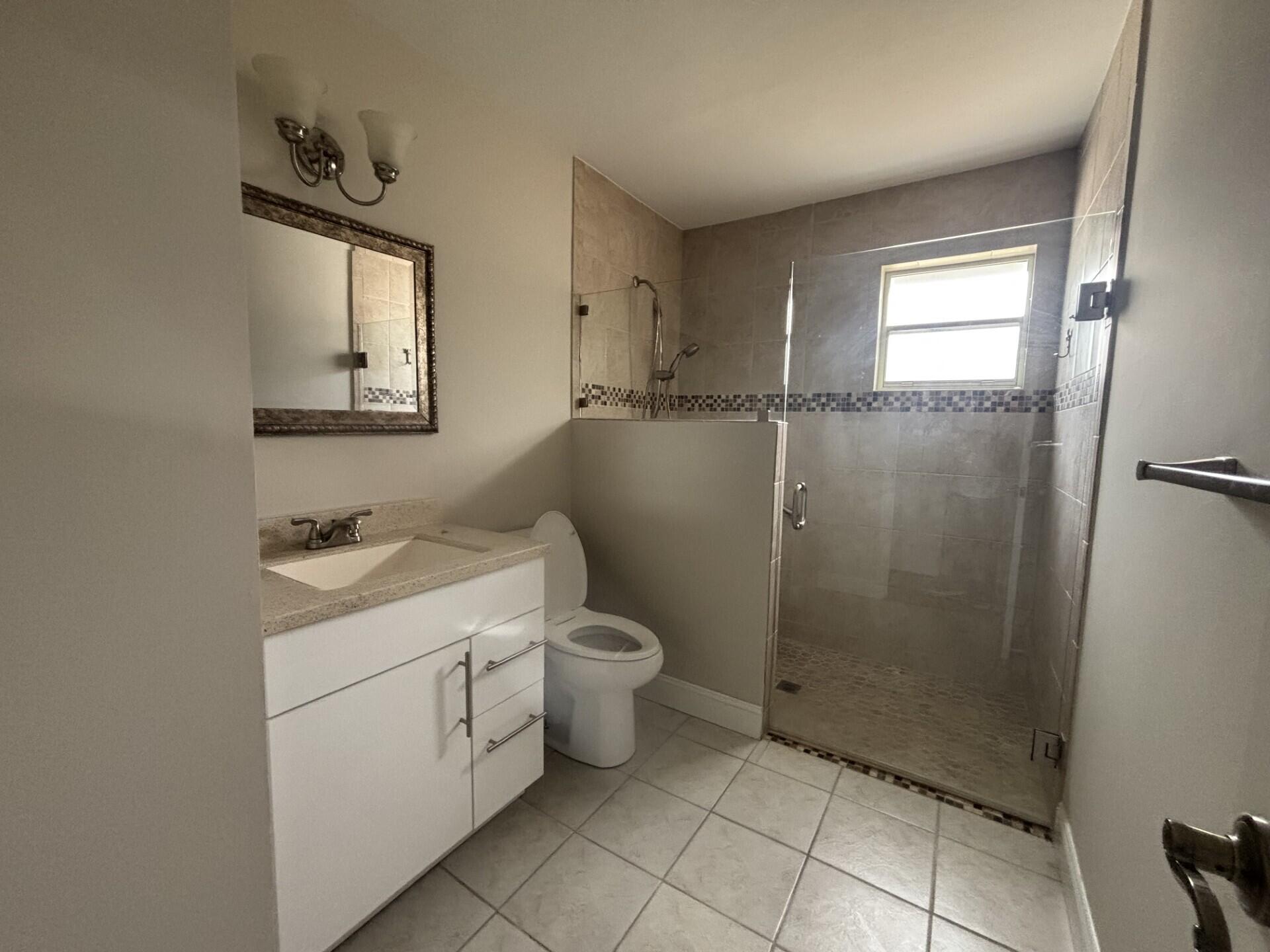 1160 East 12th Street Stuart, FL 34996 - Photo 20 of 25 a bathroom with a granite countertop sink a toilet and a mirror