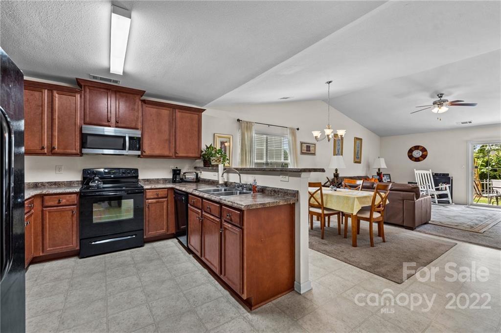 3005 Arthur Road, Unit 170 Indian Land, SC 29707 - Photo 20 of 38 a kitchen with stainless steel appliances granite countertop a stove top oven a sink dishwasher a dining table and chairs with wooden floor