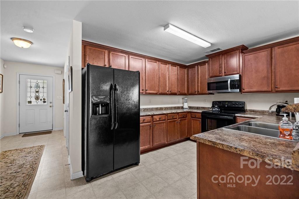 3005 Arthur Road, Unit 170 Indian Land, SC 29707 - Photo 21 of 38 a kitchen with granite countertop wooden cabinets a refrigerator and a sink
