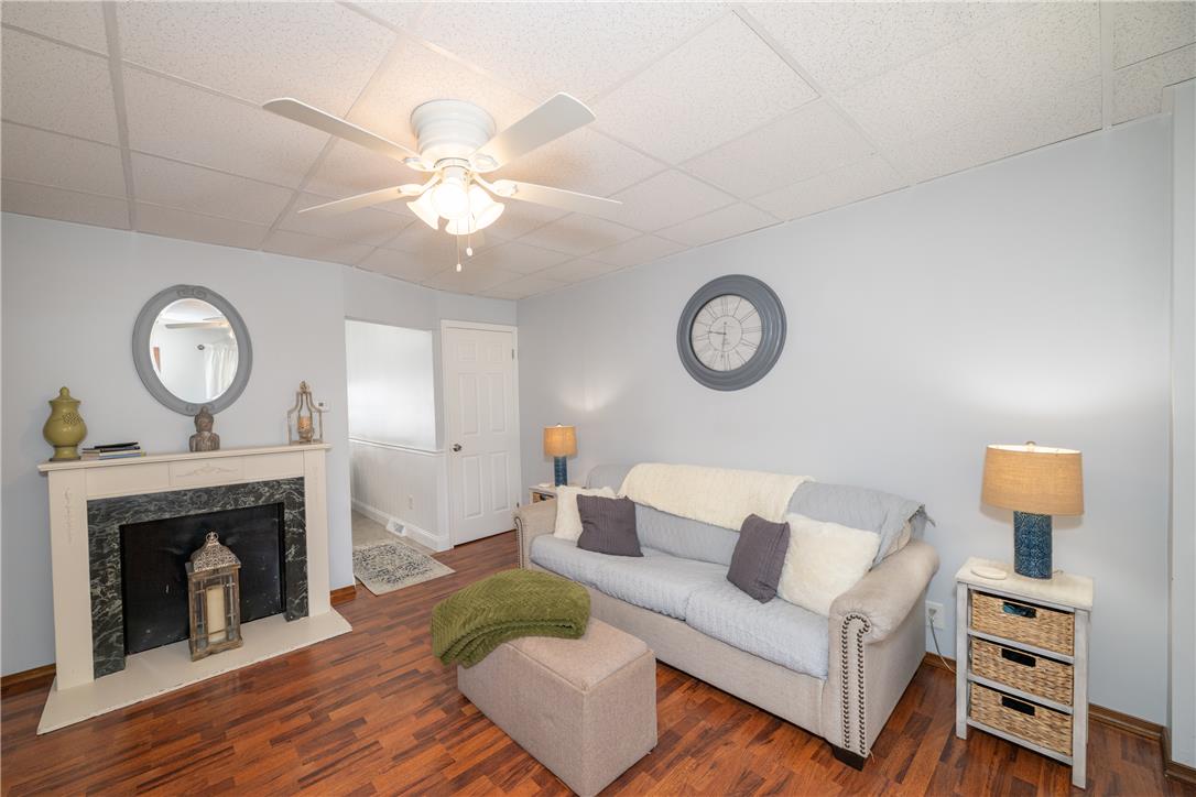 A comforting living space features a cozy fireplace and rich hardwood flooring, topped with a functional ceiling fan.