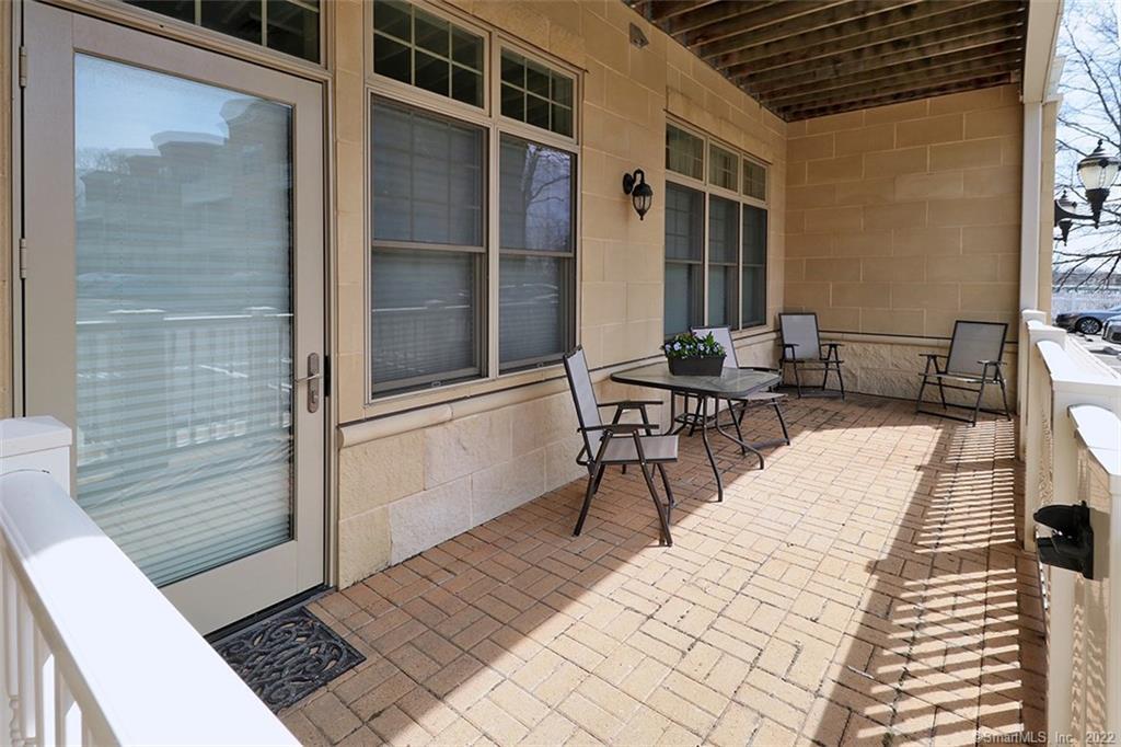 100 Stone Ridge Way, Unit 1H Fairfield, CT 06824 - Photo 13 of 30 a patio with glass top table and chairs