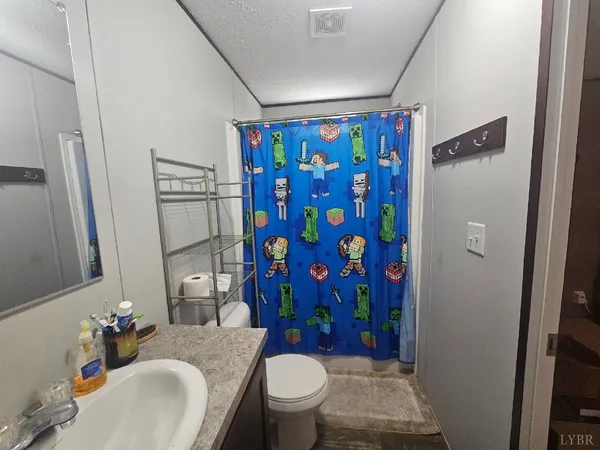 a bathroom with a granite countertop toilet sink and shower curtain