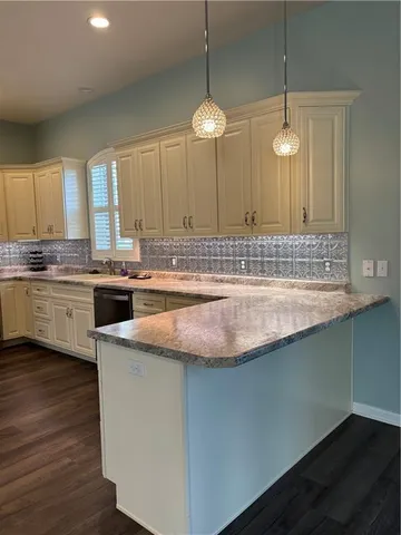 a kitchen with kitchen island granite countertop a sink a counter space appliances and cabinets