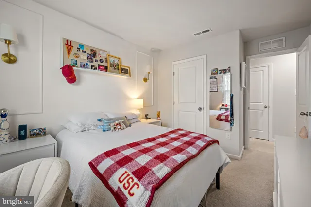 a bedroom with a bed a standing fan and a dresser