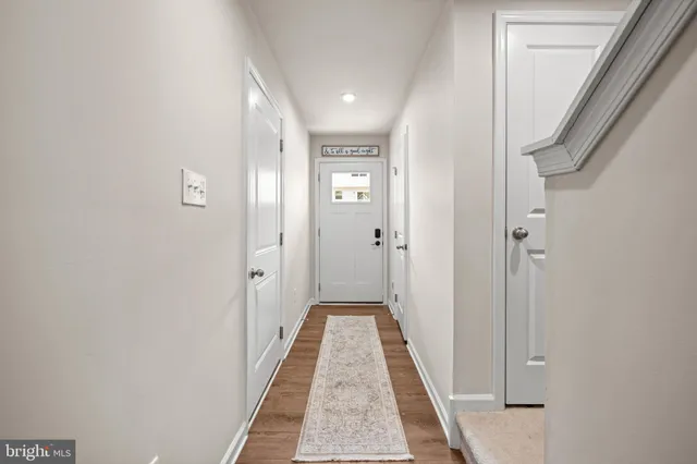 a view of a hallway with wooden floor and a bathroom