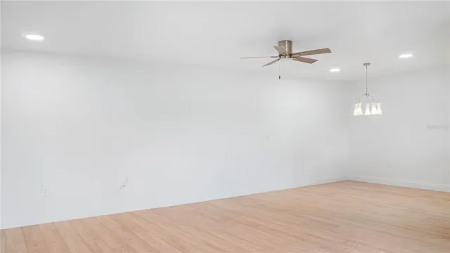an empty room with a ceiling fan and kitchen view
