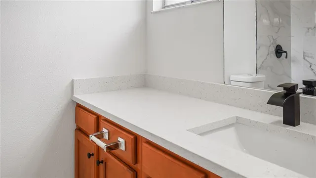 a bathroom with a granite countertop sink a toilet and shower
