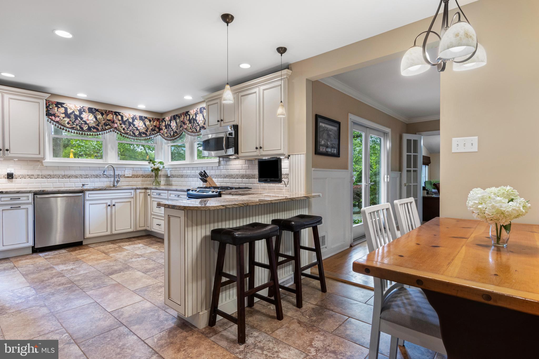 413 Hawthorne Road Wallingford, PA 19086 - Photo 20 of 52 a kitchen with stainless steel appliances kitchen island granite countertop a dining table chairs and white cabinets