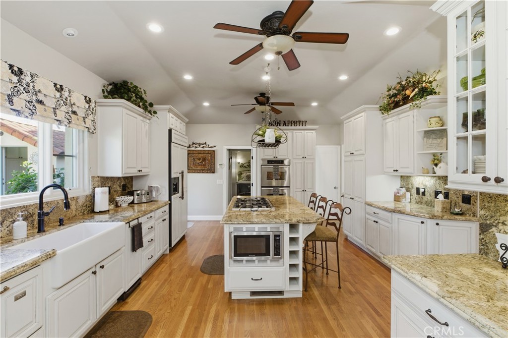 2855 McAllister Street Riverside, CA 92503 - Photo 37 of 75 a large kitchen with stainless steel appliances kitchen island granite countertop a large center island a sink dishwasher a stove and a dining table with wooden floor