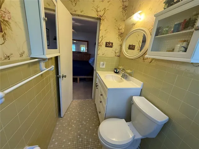a white toilet sitting next to a bathroom sink and a mirror