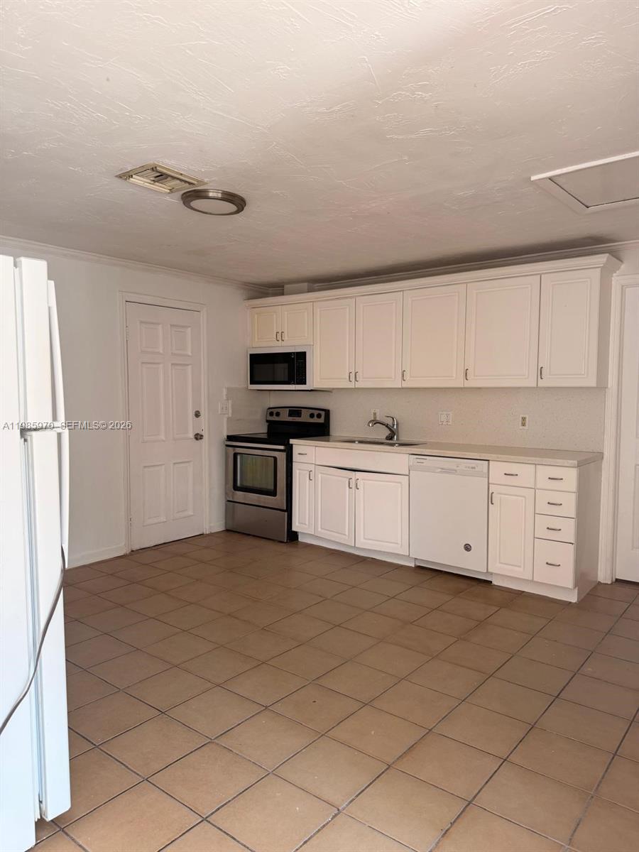409 Northwest 33rd Street, Unit 1 Miami, FL 33127 - Photo 4 of 17 a kitchen with stainless steel appliances granite countertop a stove a sink and white cabinets