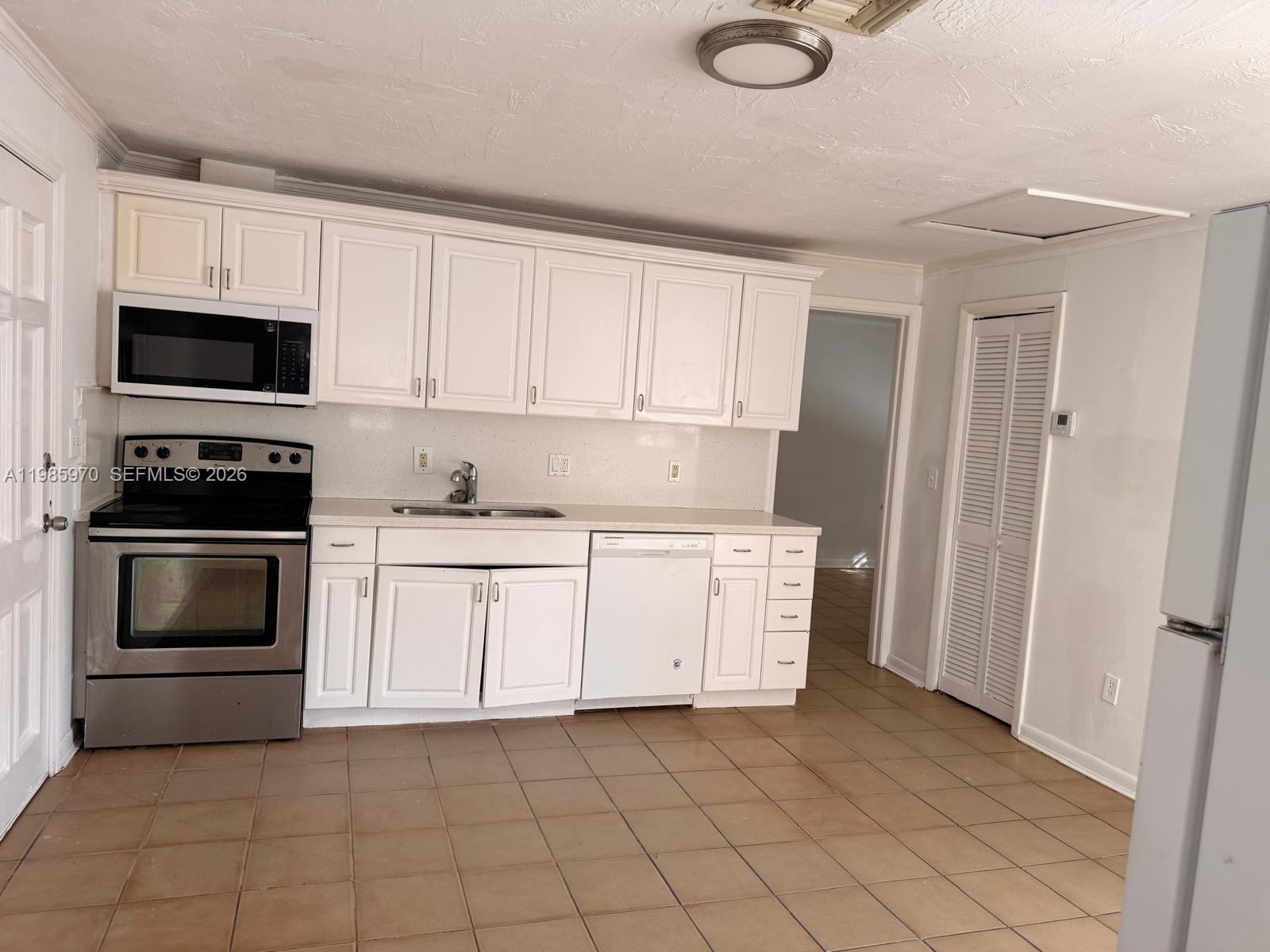 409 Northwest 33rd Street, Unit 1 Miami, FL 33127 - Photo 5 of 17 a kitchen with granite countertop white cabinets and stainless steel appliances