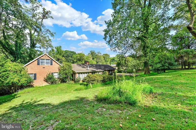 a view of a house with a big yard plants and large trees