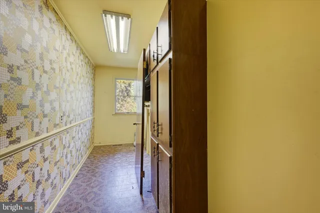 an empty room with chandelier fan and windows