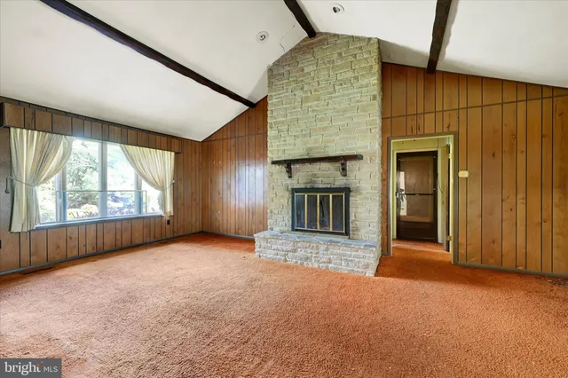 an empty room with windows and fireplace