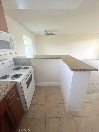 a kitchen with granite countertop a sink a stove and cabinets