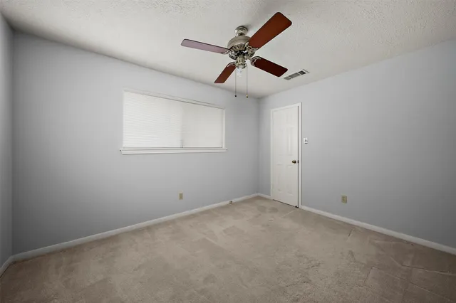 an empty room with a ceiling fan and windows