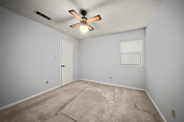 an empty room with ceiling fan and window