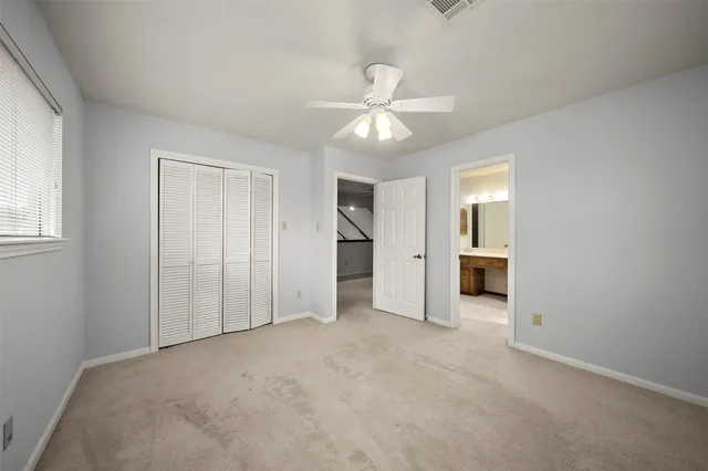 an empty room with a bathroom and a ceiling fan