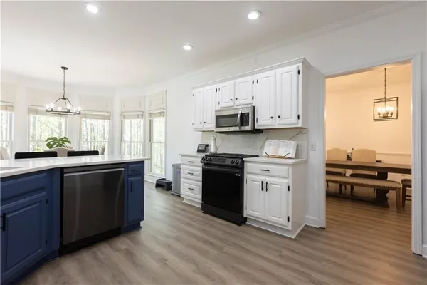 a kitchen with stainless steel appliances granite countertop a stove top oven a sink dishwasher and a refrigerator with wooden floor