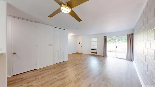 an empty room with wooden floor chandelier fan and windows