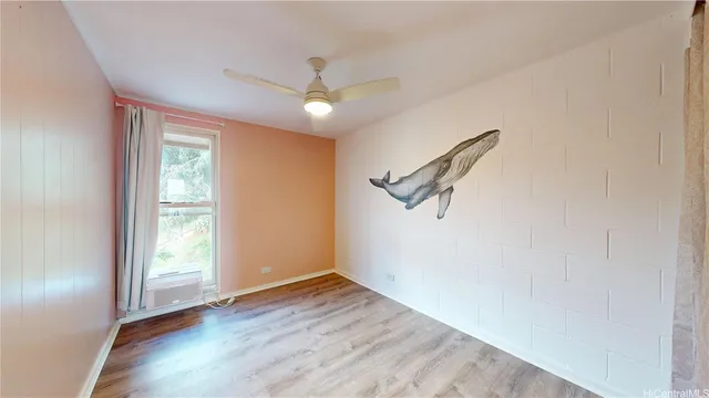an empty room with wooden floor fan and windows