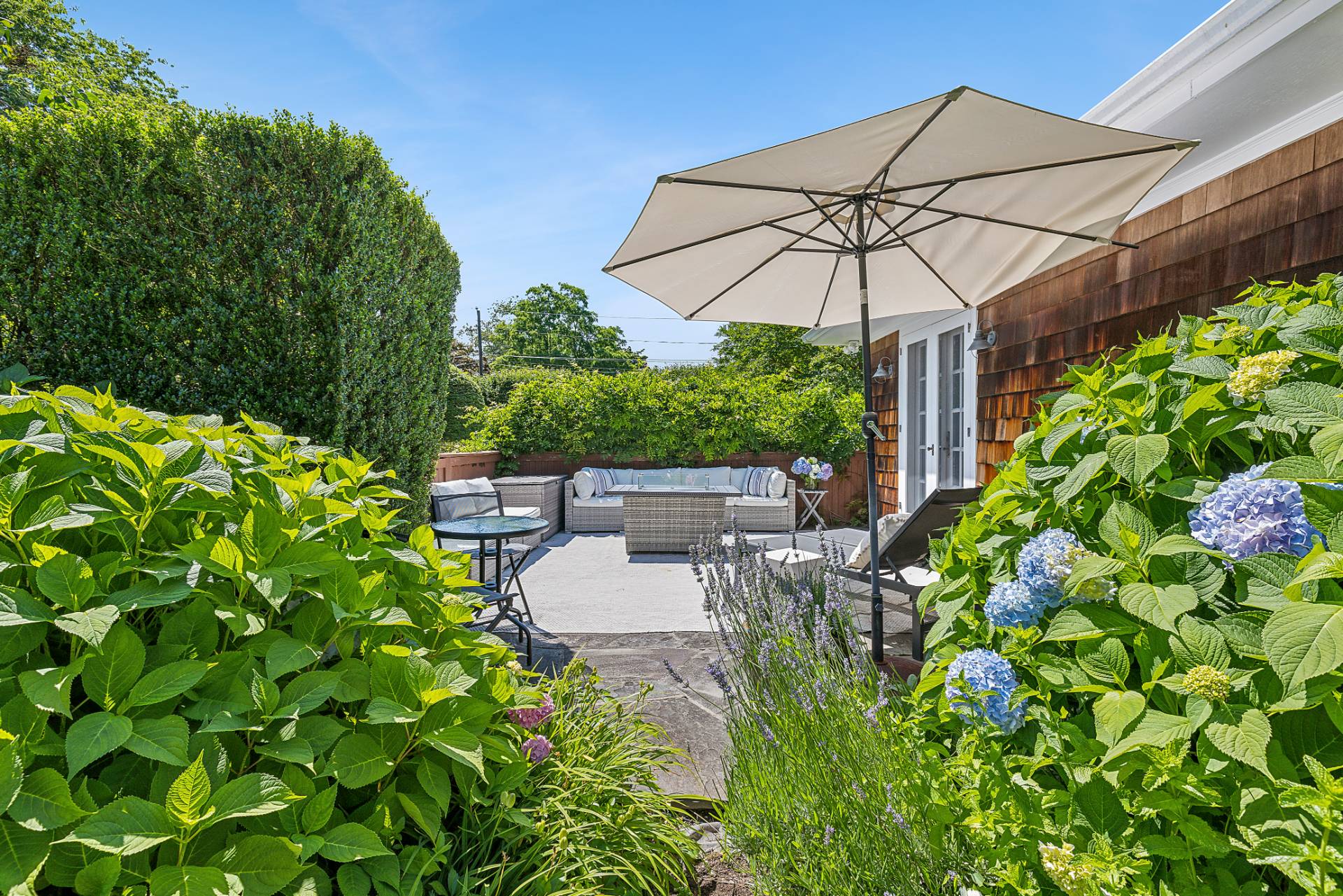 5 Coves End Lane Sag Harbor, NY 11963 - Photo 24 of 26 a backyard of a house with table and chairs under an umbrella